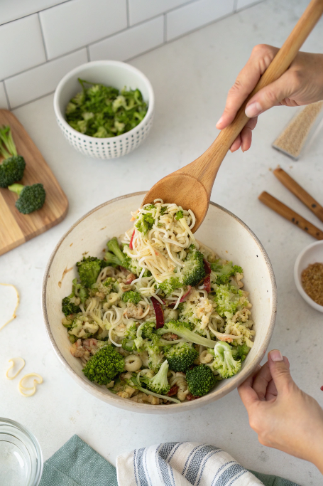 Mixing broccoli ramen noodle salad before serving